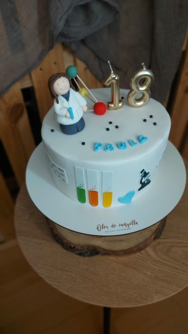 Tarta de cumpleaños con decoración de científico y el número 18.